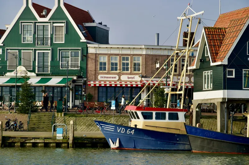 De dijk van Volendam met terrassen en een vissersboot in de haven